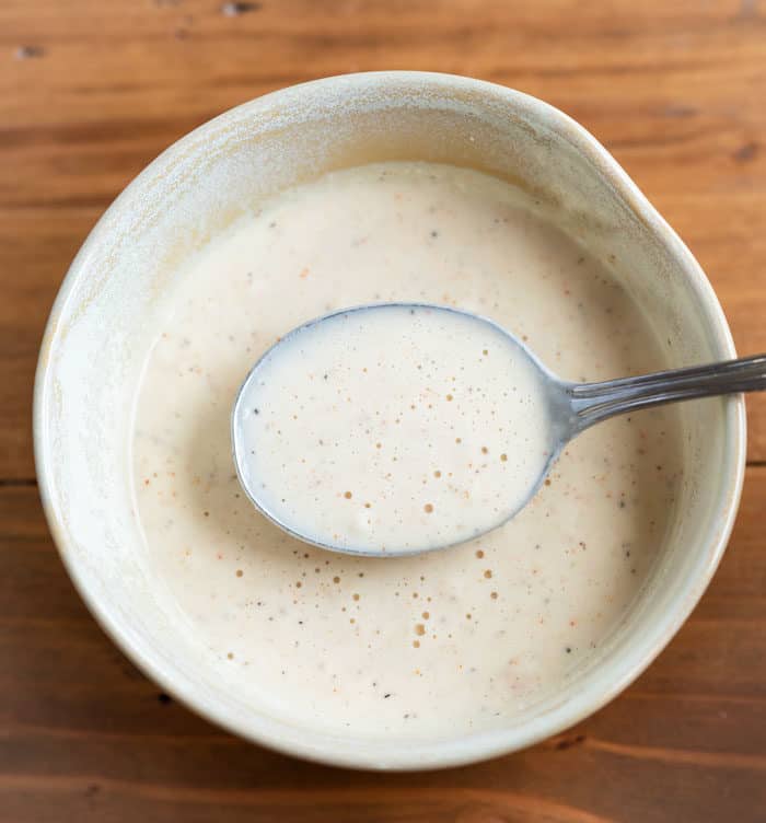 A bowl of batter with a spoon in it for making fried pickles.