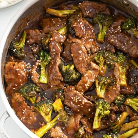 A skillet filled with beef and broccoli in a brown sauce topped with sesame seeds.