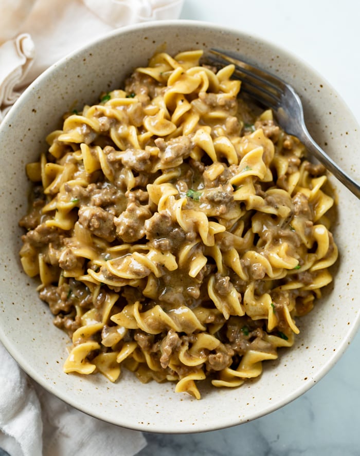 A bowl filled with creamy Beef and Noodles with a fork.