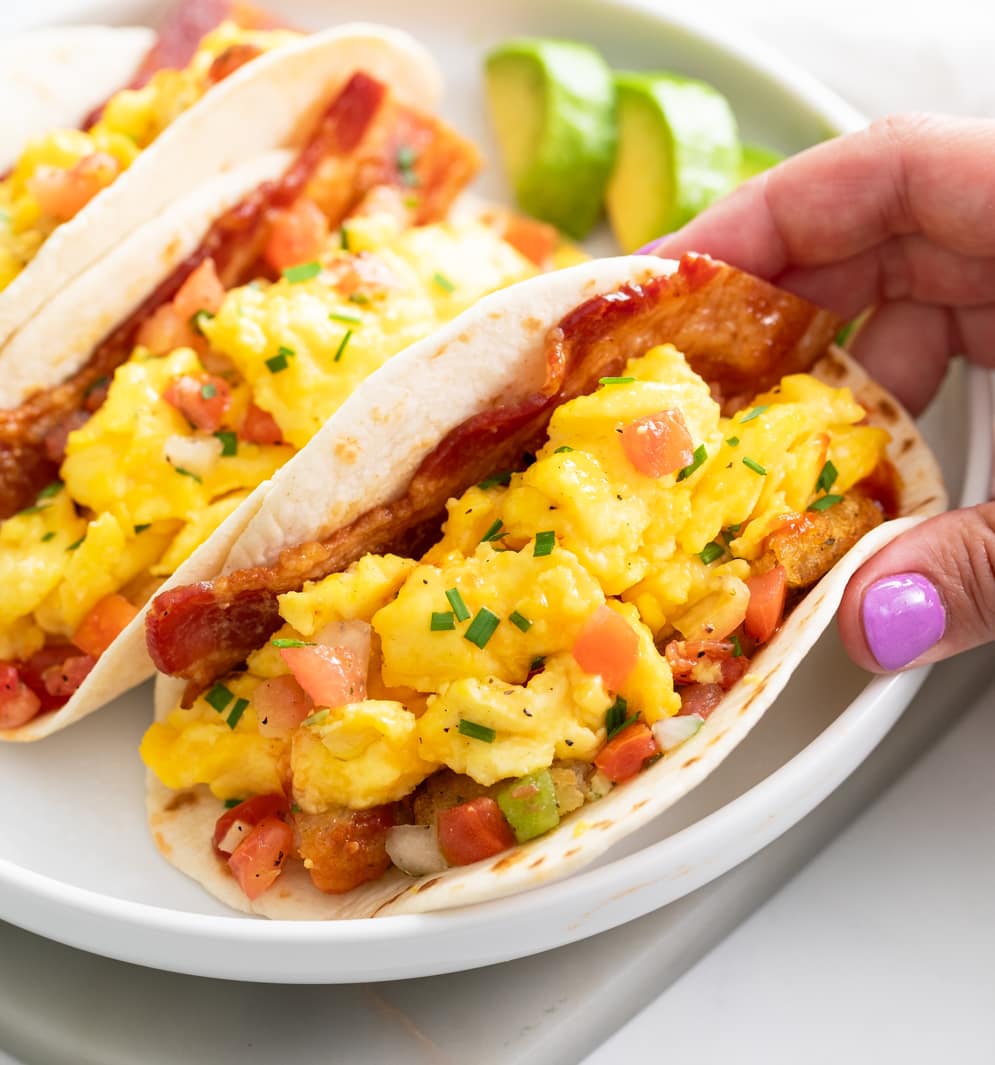 Breakfast Tacos in a flour tortilla with a hand holding one end.