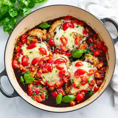 Bruschetta Chicken in a skillet with Balsamic sauce, diced tomatoes, and basil.