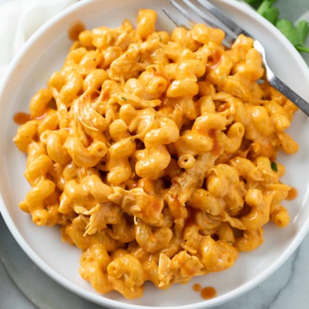 A white plate with Buffalo Chicken Mac and Cheese and a fork on the side.