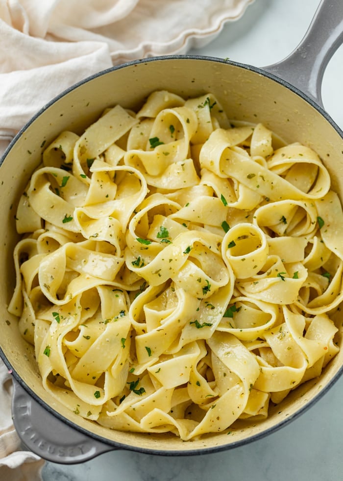 A pot filled with Buttered Noodles with herbs and fresh parsley.