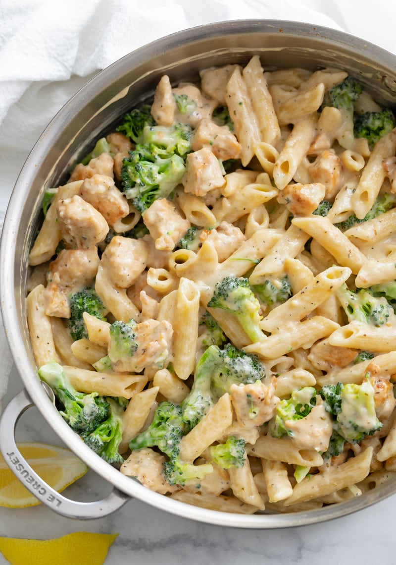 A big pot filled with Chicken and Broccoli Pasta with lemon slices on the side.