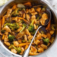 A skillet filled with Chicken and Broccoli with a spoon in the skillet.