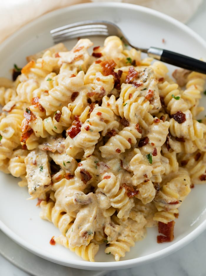 Creamy Chicken Bacon Ranch Pasta on a white plate with a fork.