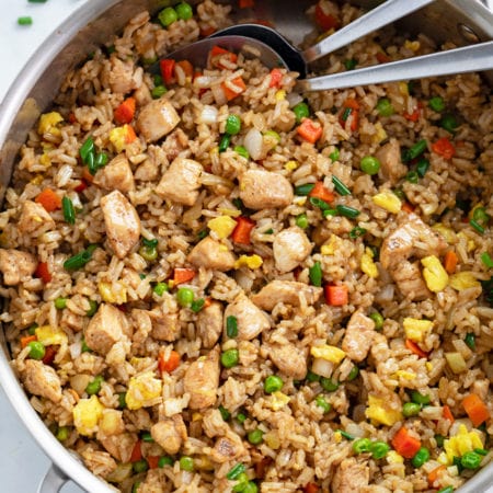 A skillet filled with Chicken Fried Rice with spoons in it.