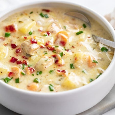 Chicken Potato Soup in a white bowl with bacon and chives on top.