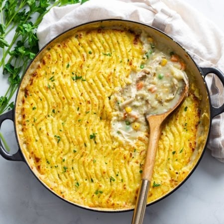 A round dish filled with Chicken Shepherd's Pie with a spoon in it.