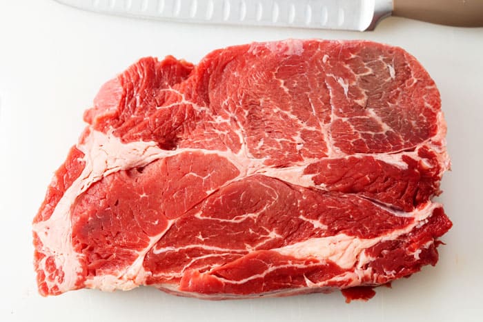 A raw chuck roast on a cutting board.