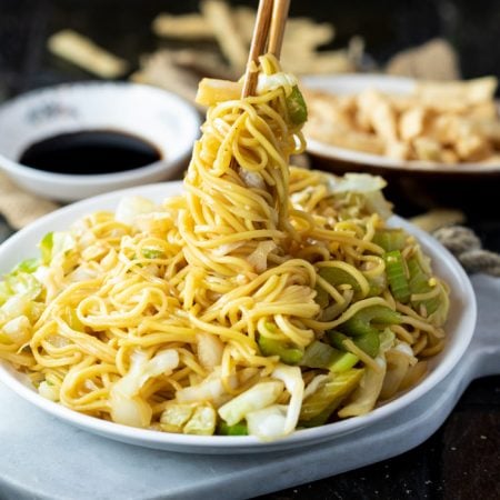 A white plate with Panda Express Chow Mein being twisted up with chopsticks.