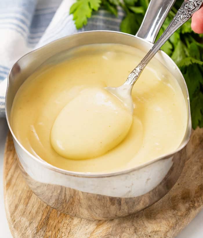 A saucepan with homemade cream of chicken soup with a spoon stirring it.