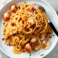 Creamy Bacon Pasta on a white plate with cherry tomatoes and crispy chopped bacon.