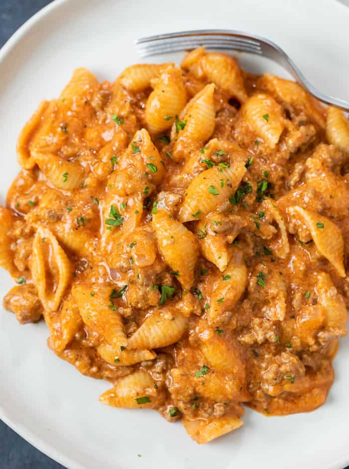 Creamy Beef and Shells on a white plate with a fork. 