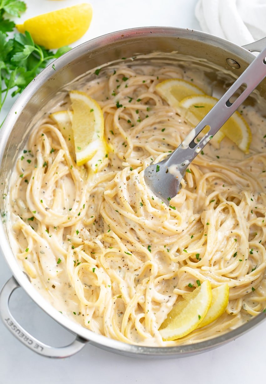 A skillet filled with Creamy Herb Pasta with lemon slices.