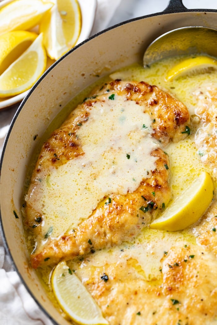 Creamy Lemon Chicken in a skillet with lemon wedges and parsley.