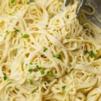 Garlic Parmesan Pasta in a skillet with kitchen tongs topped with parsley.