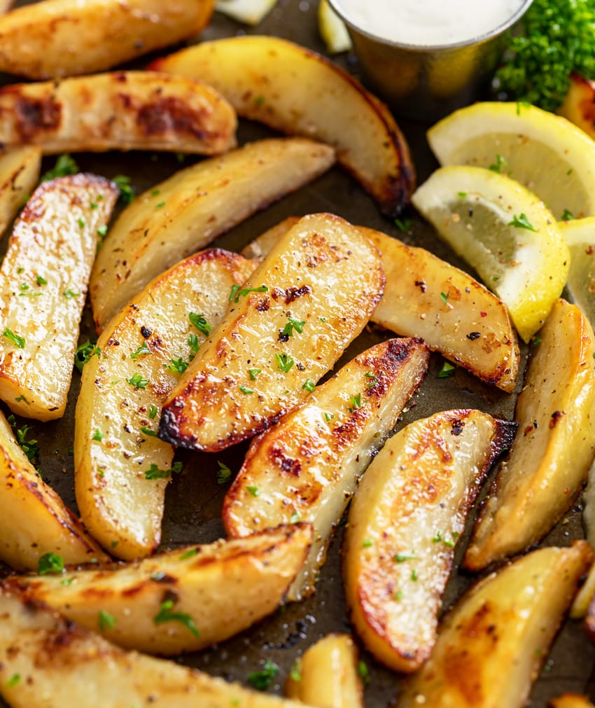 Greek Potatoes on a roasting pan with lemon slices and parsley.