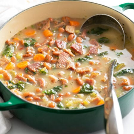 Ham Soup in a green Dutch oven with a metal ladle.