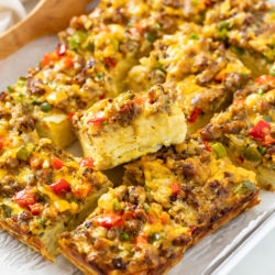 Slices of Hashbrown Breakfast Casserole topped sausage, cheese, and peppers.