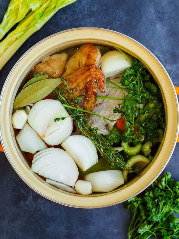 Overhead view of ingredients for homemade chicken stock in a stock pot.