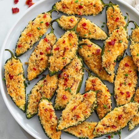 A plate of Jalapeno Poppers with chives and bacon on top.