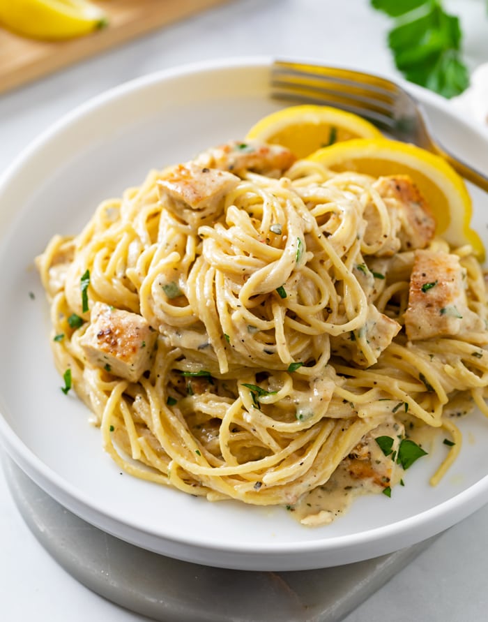 Lemon Chicken Pasta on a white plate with lemon wedges.