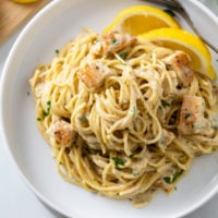 Lemon Chicken Pasta on a white plate with a fork and lemon slices.