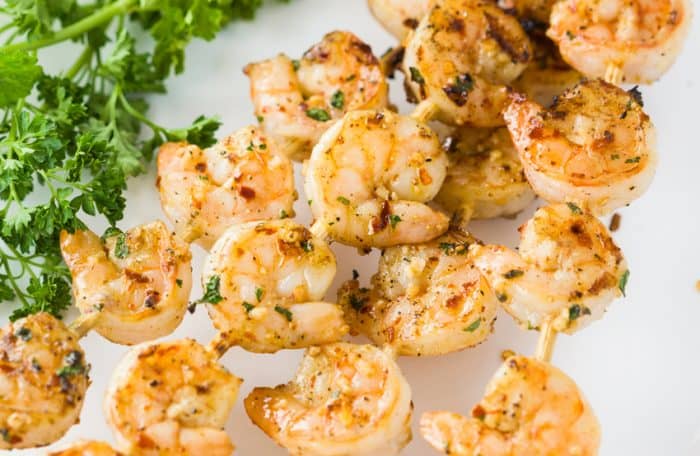 Lemon Garlic Shrimp on skewers next to fresh parsley.