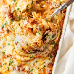 A spoon scooping a cheesy Pasta Bake up from a casserole dish.