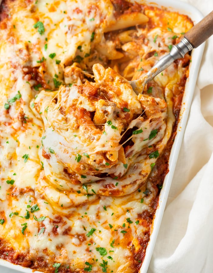 A spoon scooping a cheesy Pasta Bake up from a casserole dish.