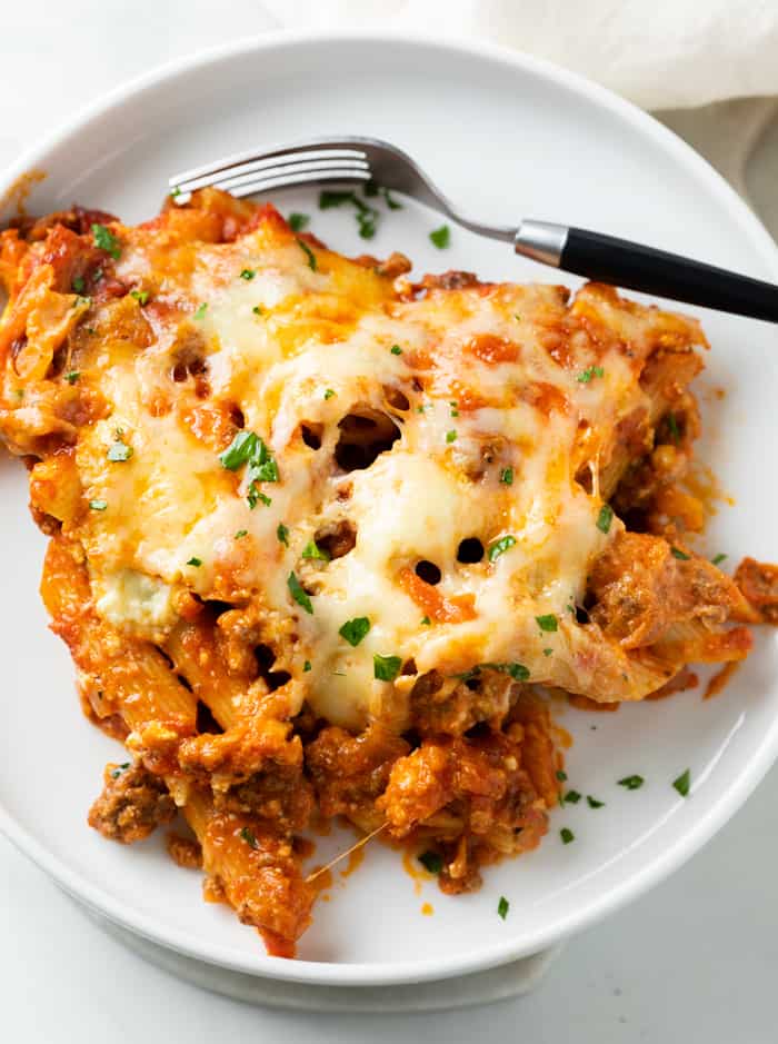 Cheesy Pasta Bake on top of a white plate with a fork and fresh parsley.