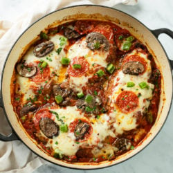 A round skillet filled with Pizza Chicken with mozzarella cheese and pizza toppings.