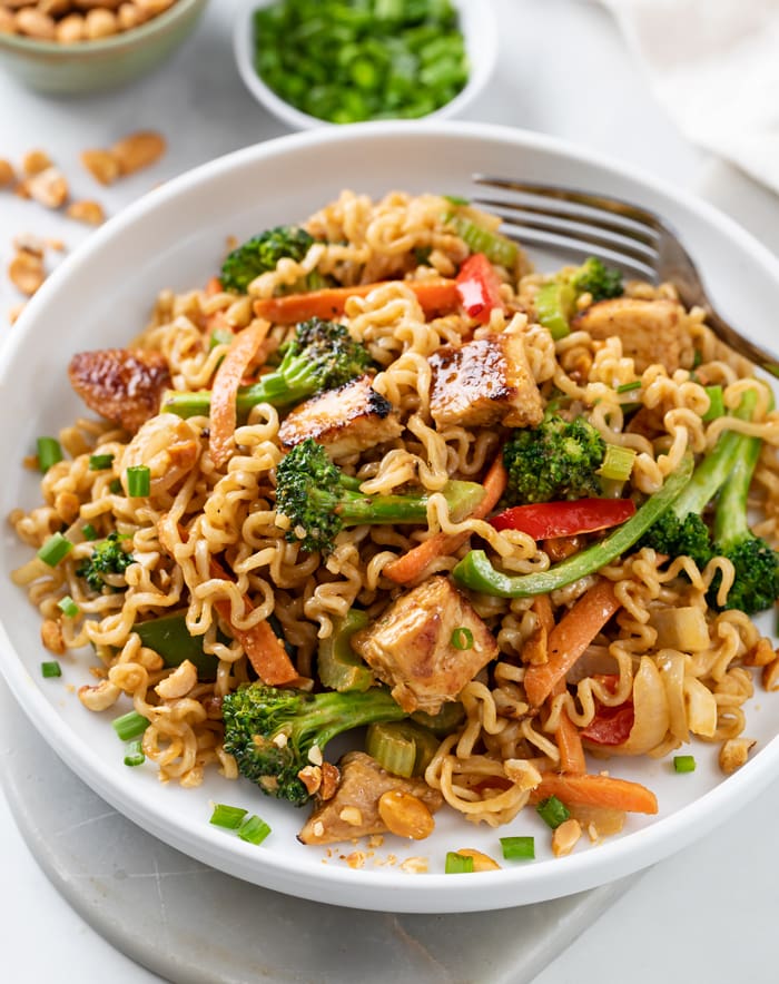 A white plate with Ramen Noodle Stir Fry with chicken and sauce.