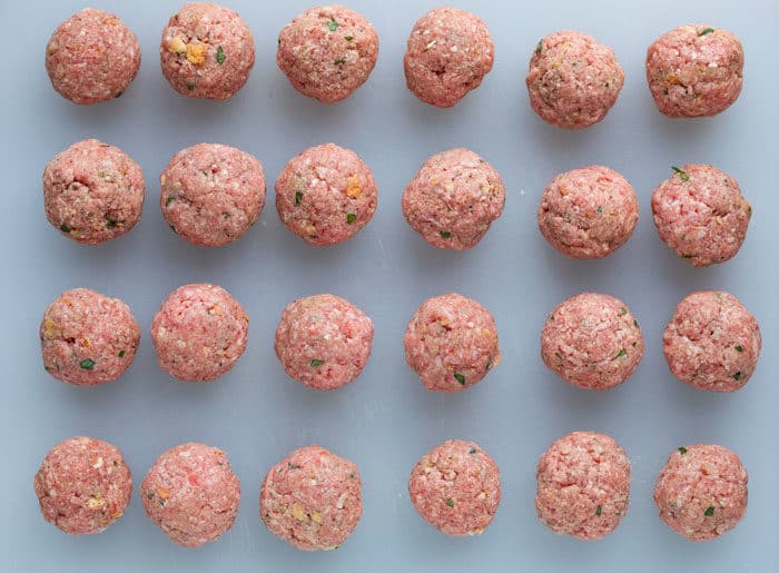 Uncooked meatballs rolled out on a white surface