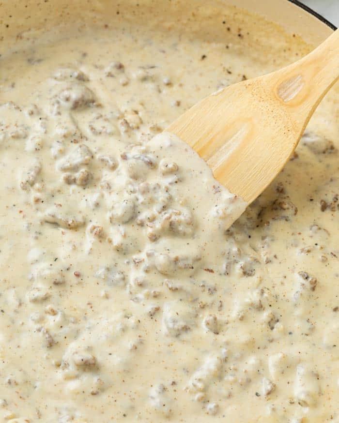 A skillet with a spatula stirring sausage gravy.