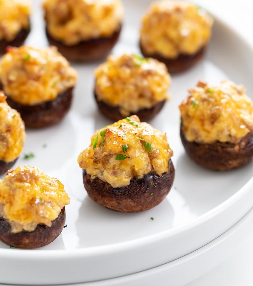 A white plate with Sausage Stuffed Mushrooms on it.