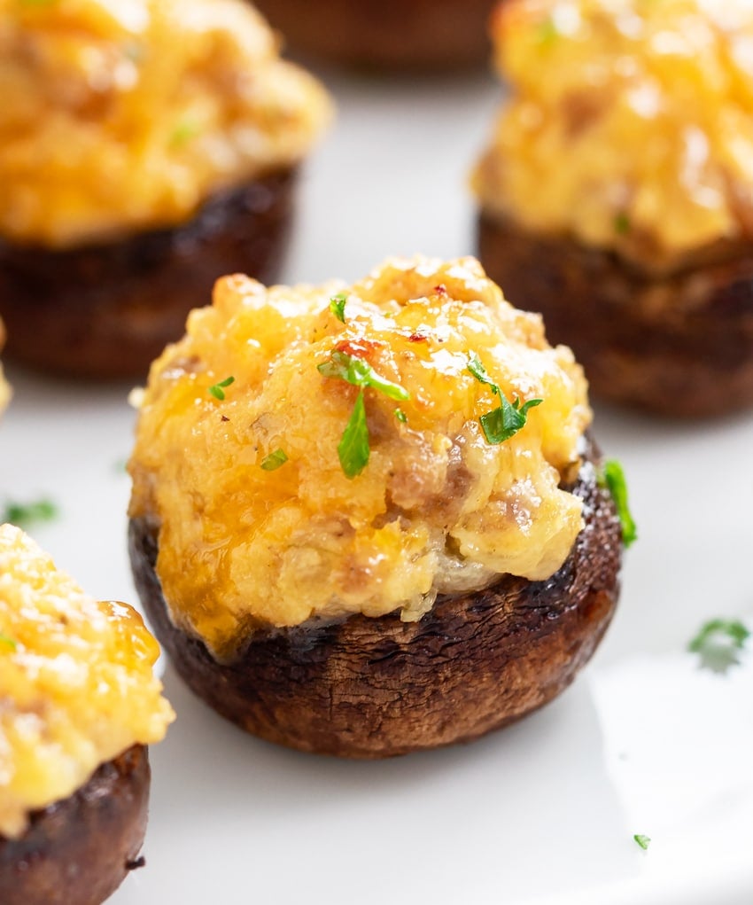 A Sausage Stuffed Mushroom on a white plate with parsley on top.