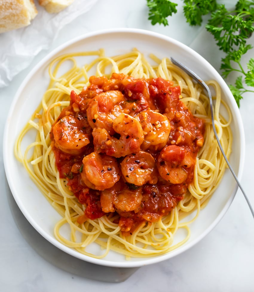 A white plate with Shrimp Fra Diavolo over linguine.