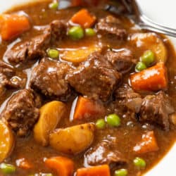 A white bowl filled with Slow Cooker Beef Stew with a spoon in the background.