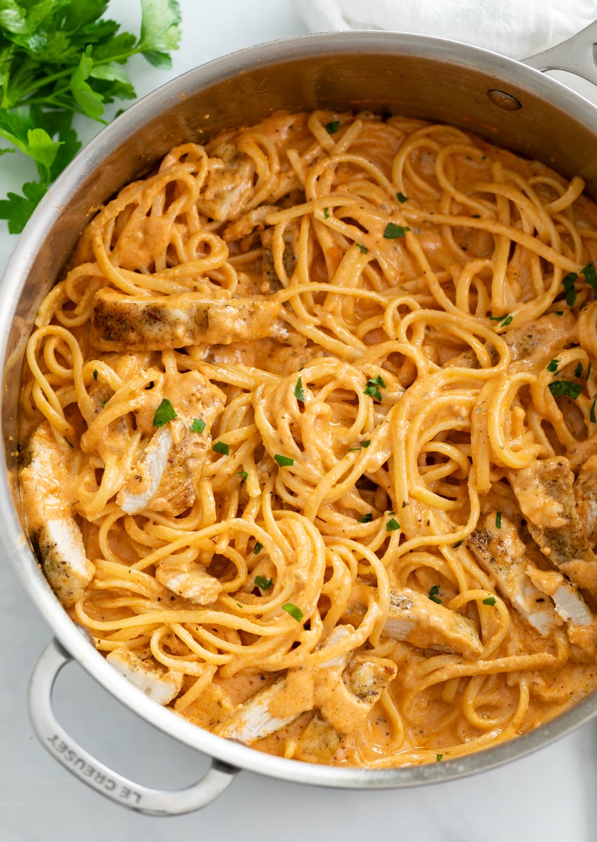 A skillet filled with Creamy Tomato Pasta with Chicken and parsley.