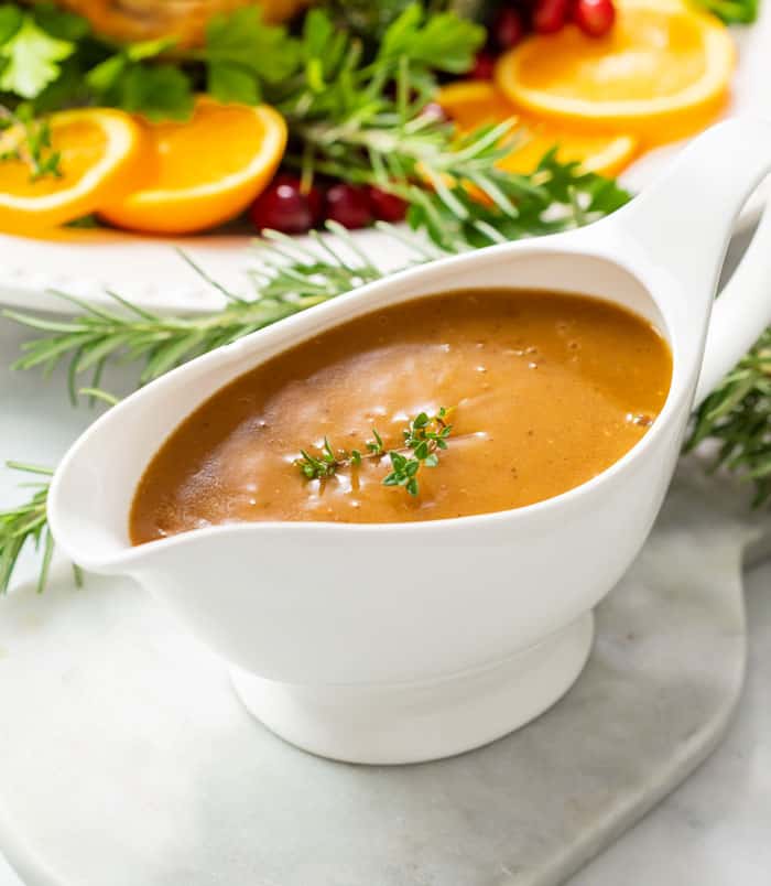 Thick brown turkey gravy in a gravy boat topped with fresh thyme.