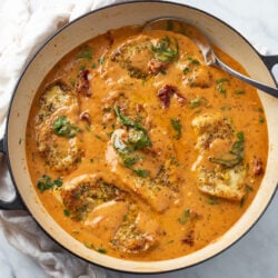 A skillet filled with Tuscan Chicken in sauce with sundried tomatoes and spinach.