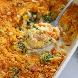 A spoon scooping up Vegetable Casserole from a baking dish.