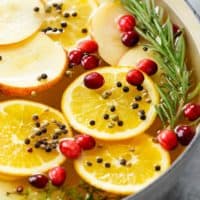 A pot filled with sliced fruit, herbs, and peppercorns for wet brine.