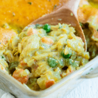 A wooden spoon scooping Bisquick Chicken Pot Pit from a casserole dish.